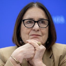Irina Scherbakowa sitzt den Kopf auf die Hände gestützt vor einem blauen Hintergrund. Sie trägt einen großen goldenen Ring und eine schwarz umrandete Brille.