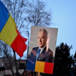 Ein Plakat mit einem Porträt von Călin Georgescu neben einer rumänischen Flagge am 26. Februar 2025. Der rechtsextreme Kandidat wird bei der Wiederholungswahl am 