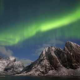 Der grüne Schein der Nordlichter über einem Berg in den Lofoten, Norwegen.